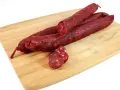 Kilka kawałków chorizo na desce do krojenia. To pikantna, suszona kiełbasa wieprzowa, idealna do tapas.