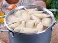 Pierogi gotują się w garnku. Woda wrze, a pierożki wypływają na powierzchnię. Czas gotowania pierogów jest kluczowy dla ich smaku.