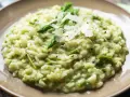 Kremowe risotto ze szparagami, posypane płatkami parmezanu i świeżo mielonym pieprzem.