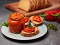 Słoik ajvaru i pieczywo z pastą. Ajvar do czego? Idealny na kanapki, dodatek do mięs i warzyw.