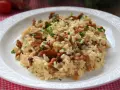 Aksamitne risotto z kurkami, posypane świeżą natką pietruszki, prezentuje się apetycznie na białym talerzu.