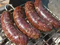 Cztery soczyste kaszanki z grilla pieką się na ruszcie, uwalniając apetyczny aromat.