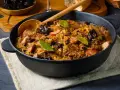 Pyszny bigos w żeliwnym naczyniu, z widocznymi kawałkami mięsa, śliwkami i liśćmi laurowymi. Idealne danie, gdy zastanawiasz się, jakie mięso do bigosu wybrać.