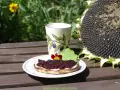 Pyszny tost z kremem i dżemem z czarnej porzeczki, idealny pomysł co zrobić z czarnej porzeczki. Obok kubek i słonecznik.