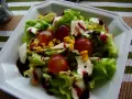 Sałatka z sosem winegret: chrupiąca sałata, winogrona, kukurydza i ser mozzarella polane ciemnym sosem.