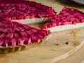 Pyszna tarta z rabarbarem, z kremowym nadzieniem i chrupiącym spodem, prezentuje się apetycznie na drewnianej desce.