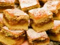 Szybkie ciasto z jabłkami, pokrojone w kostkę i posypane cukrem pudrem, wygląda apetycznie.