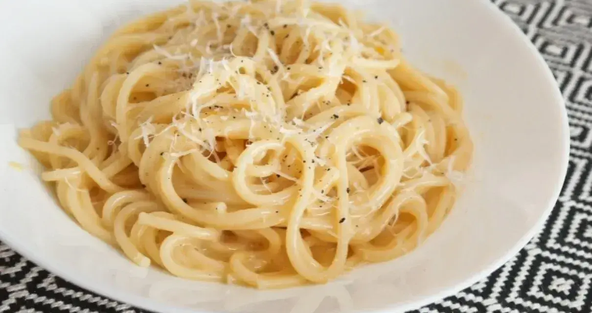 Pyszne spaghetti carbonara przepis na talerzu, posypane parmezanem i świeżo mielonym pieprzem.