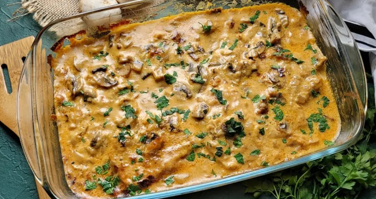 Pyszny schab w sosie grzybowym, zapieczony w naczyniu żaroodpornym, posypany świeżą natką pietruszki.
