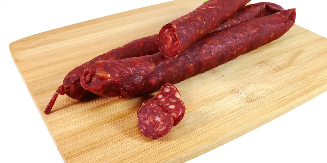 Kilka kawałków chorizo na desce do krojenia. To pikantna, suszona kiełbasa wieprzowa, idealna do tapas.