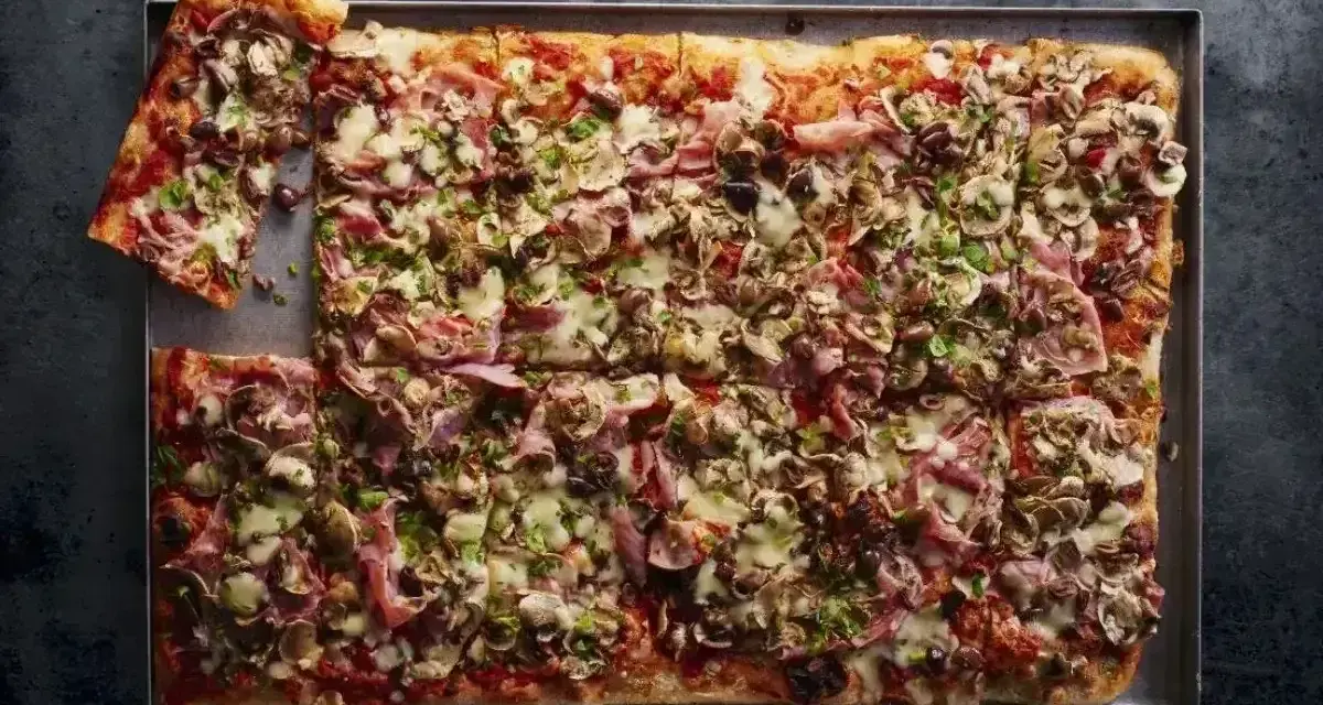 Pyszna pizza domowa przepis na blachę z szynką, pieczarkami i oliwkami. Idealna na rodzinne spotkanie.