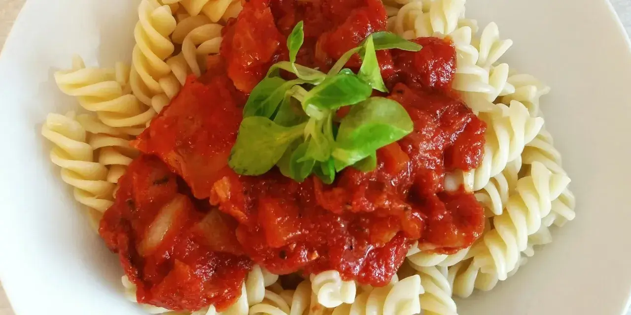 Szybki obiad z makaronem fusilli i sosem pomidorowym, udekorowany świeżą zieleniną. Idealny na szybki posiłek.