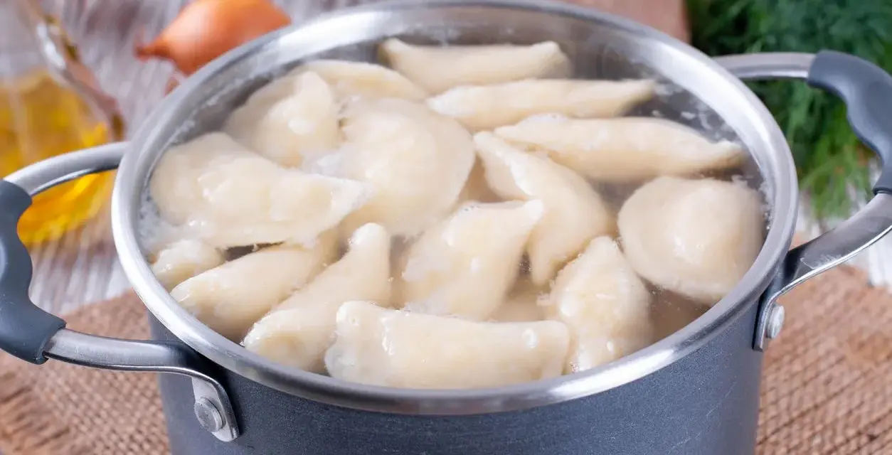 Pierogi gotują się w garnku. Woda wrze, a pierożki wypływają na powierzchnię. Czas gotowania pierogów jest kluczowy dla ich smaku.