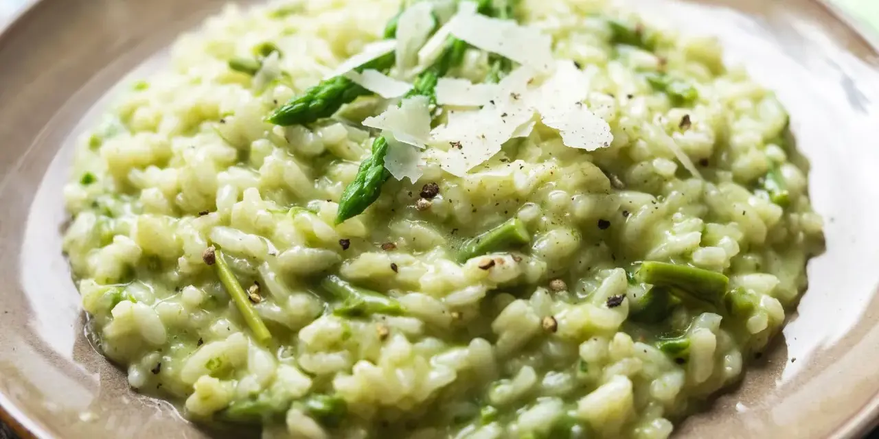 Kremowe risotto ze szparagami, posypane płatkami parmezanu i świeżo mielonym pieprzem.