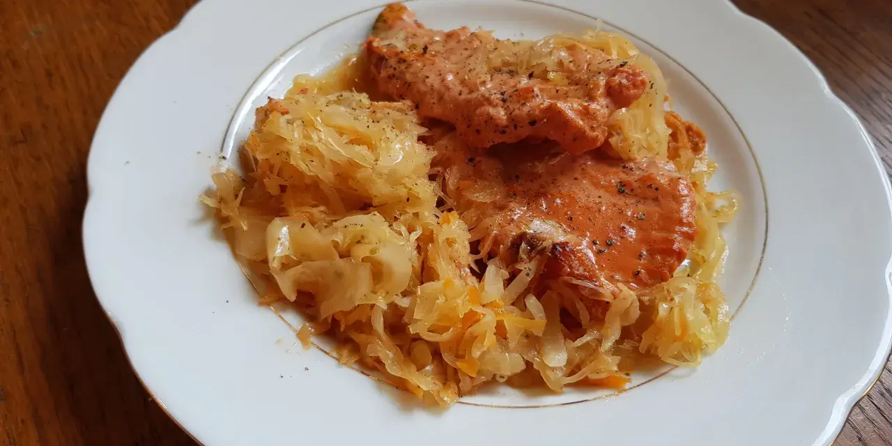 Schab w kapuście kiszonej, danie Ani, wygląda apetycznie na białym talerzu.