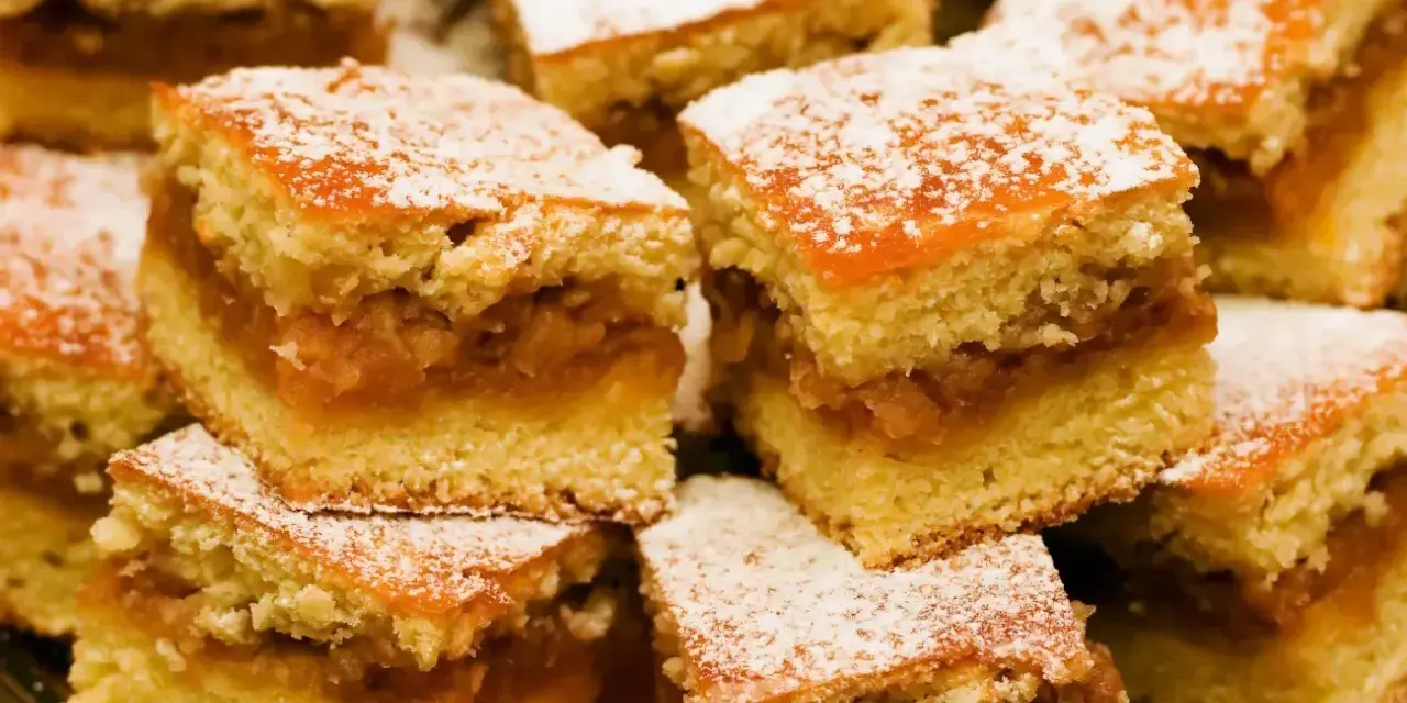 Szybkie ciasto z jabłkami, pokrojone w kostkę i posypane cukrem pudrem, wygląda apetycznie.