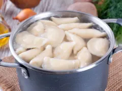 Pierogi gotują się w garnku. Woda wrze, a pierożki wypływają na powierzchnię. Czas gotowania pierogów jest kluczowy dla ich smaku.