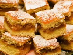 Szybkie ciasto z jabłkami, pokrojone w kostkę i posypane cukrem pudrem, wygląda apetycznie.