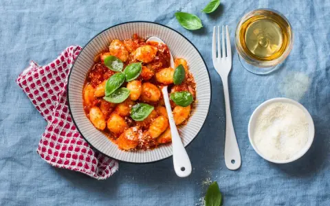 Pyszne gnocchi w sosie pomidorowym, posypane parmezanem. Idealne z kieliszkiem białego wina.