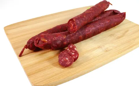 Kilka kawałków chorizo na desce do krojenia. To pikantna, suszona kiełbasa wieprzowa, idealna do tapas.