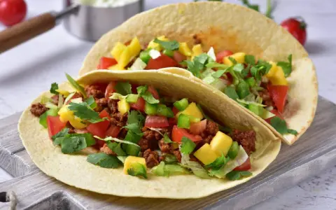 Dwa pyszne, domowe fast foody: tortille z mielonym mięsem, pomidorami, papryką, mango i świeżą kolendrą.