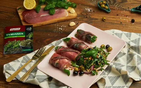 Roladki z szynką parmeńską, ziół, anchois i serka, podane z sałatką z rukoli, oliwek i orzeszków pinii.