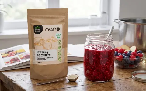 Pektyna do dżemów, cytrusowo-jabłkowa, to naturalny zagęstnik. Na stole słoik z malinowym dżemem, owoce i opakowanie produktu.