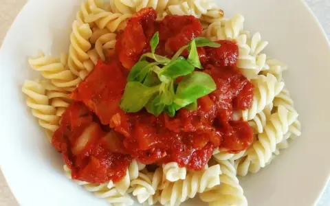 Szybki obiad z makaronem fusilli i sosem pomidorowym, udekorowany świeżą zieleniną. Idealny na szybki posiłek.