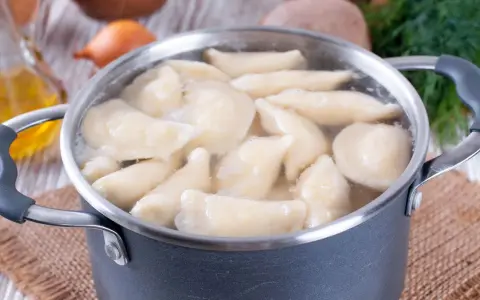 Pierogi gotują się w garnku. Woda wrze, a pierożki wypływają na powierzchnię. Czas gotowania pierogów jest kluczowy dla ich smaku.