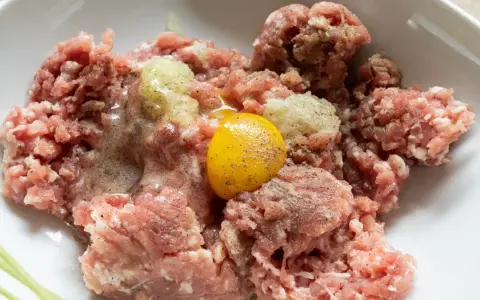 Mielone mięso z dodatkiem cebuli i jednego jajka, gotowe do dalszego przygotowania. Ile jajek do mielonych? Zazwyczaj jedno na pół kilograma mięsa.