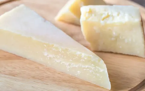 Kawałki twardego, żółtego sera na desce. Szukasz pomysłów, czym zastąpić parmezan?