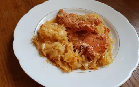 Schab w kapuście kiszonej, danie Ani, wygląda apetycznie na białym talerzu.