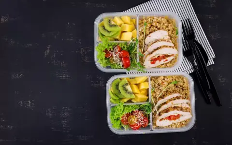 Dwa pudełka na lunch do pracy: kurczak faszerowany, kasza, sałatka z pomidorkami i kiełkami, kiwi i mango.