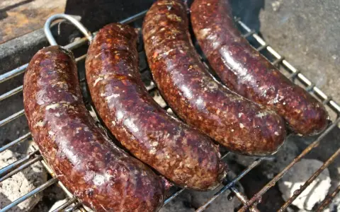 Cztery soczyste kaszanki z grilla pieką się na ruszcie, uwalniając apetyczny aromat.