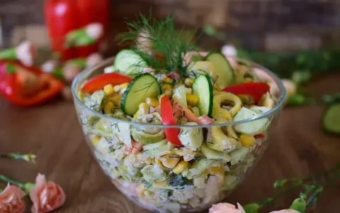 Pyszna sałatka z tortellini, ogórka, kukurydzy i papryki, udekorowana koperkiem. Idealna na letnie przyjęcie.