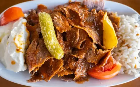 Pyszny kebab z mięsa mielonego z ryżem, jogurtem, pomidorem i pikantną papryczką.