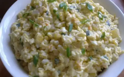 Szybka sałatka z ryżem i jajkiem, z dodatkiem szczypiorku, w białej misce. Idealna na szybki lunch.
