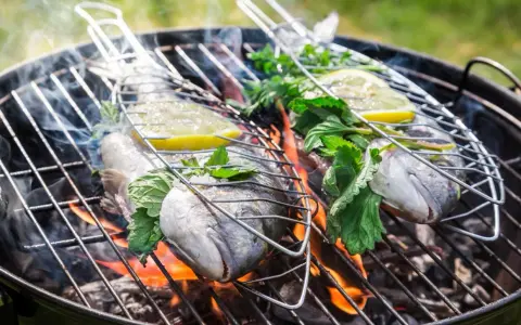 Dwie ryby na grillu, z cytryną i ziołami, unoszą się nad ogniem. Idealna jaka ryba na grilla na letni wieczór.