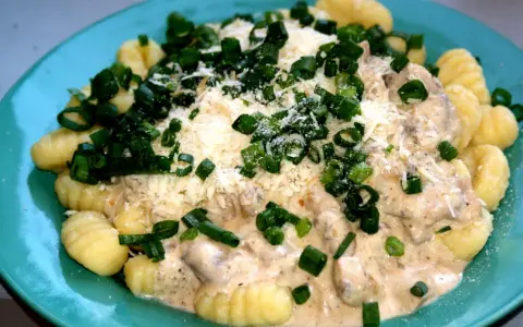 Pyszne gnocchi z kurczakiem w kremowym sosie, posypane parmezanem i szczypiorkiem.