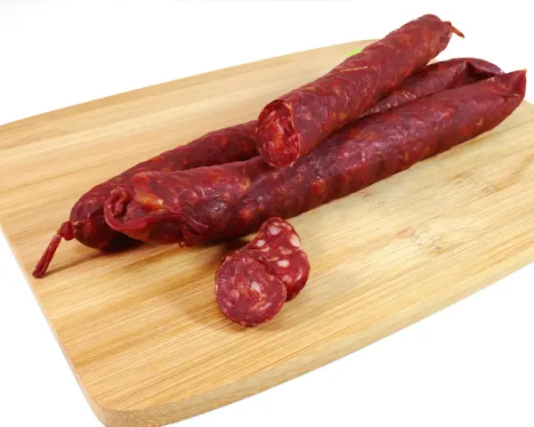 Kilka kawałków chorizo na desce do krojenia. To pikantna, suszona kiełbasa wieprzowa, idealna do tapas.