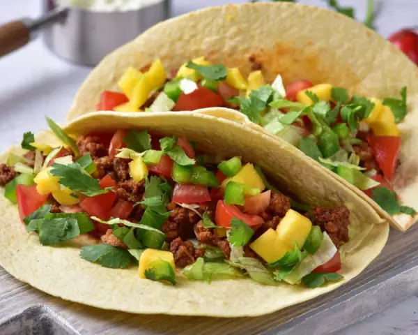 Dwa pyszne, domowe fast foody: tortille z mielonym mięsem, pomidorami, papryką, mango i świeżą kolendrą.