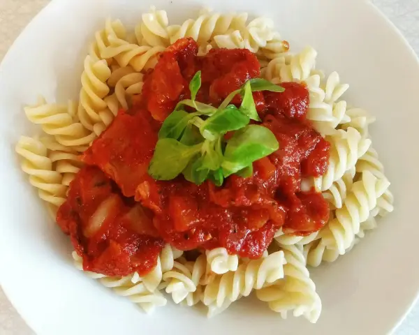 Szybki obiad z makaronem fusilli i sosem pomidorowym, udekorowany świeżą zieleniną. Idealny na szybki posiłek.
