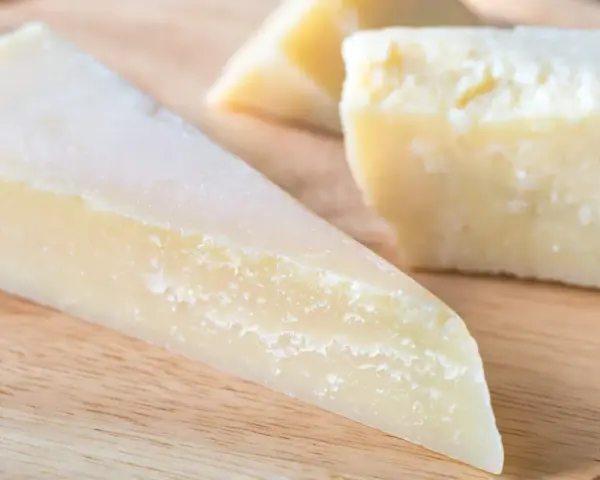 Kawałki twardego, żółtego sera na desce. Szukasz pomysłów, czym zastąpić parmezan?