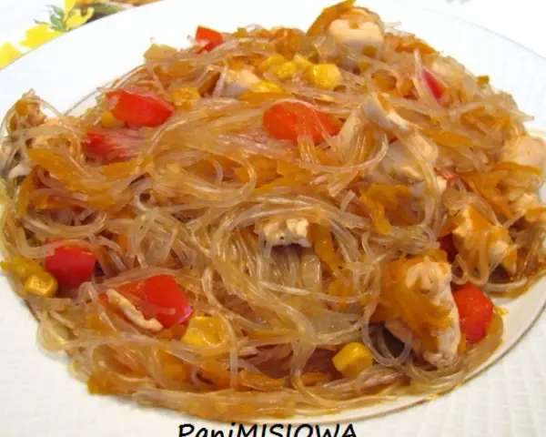 Pyszny makaron sojowy z kurczakiem, papryką i kukurydzą na białym talerzu.