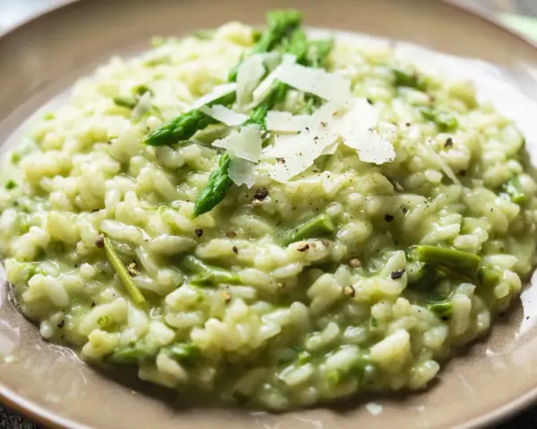 Kremowe risotto ze szparagami, posypane płatkami parmezanu i świeżo mielonym pieprzem.