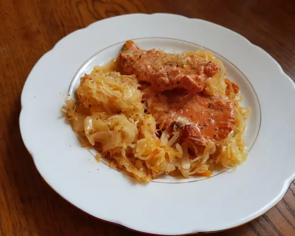 Schab w kapuście kiszonej, danie Ani, wygląda apetycznie na białym talerzu.