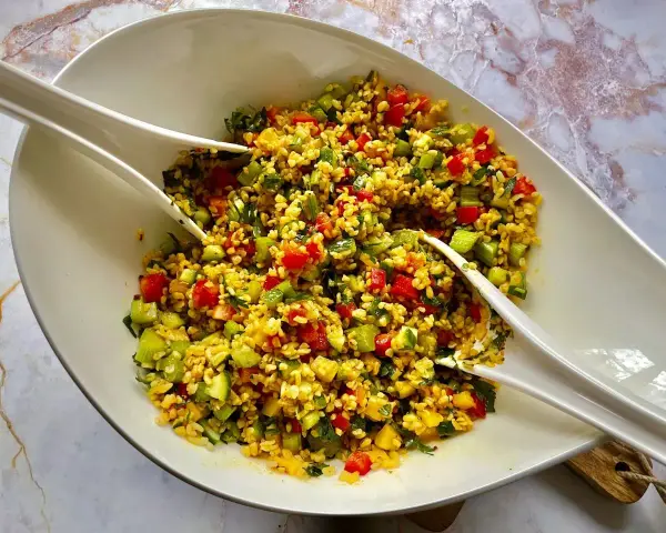 Kolorowa sałatka z kaszą bulgur, pomidorami, ogórkiem i ziołami, gotowa do podania.
