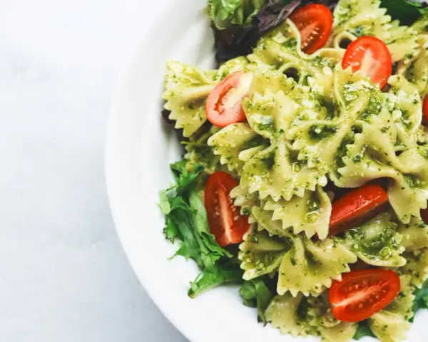 Pyszna sałatka z makaronem farfalle w sosie pesto, z pomidorkami koktajlowymi i świeżą sałatą.