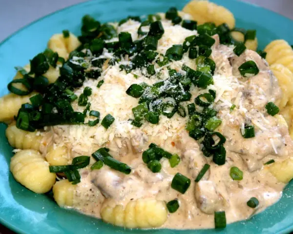 Pyszne gnocchi z kurczakiem w kremowym sosie, posypane parmezanem i szczypiorkiem.