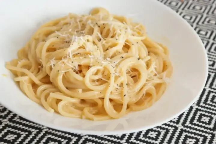Pyszne spaghetti carbonara przepis na talerzu, posypane parmezanem i świeżo mielonym pieprzem.